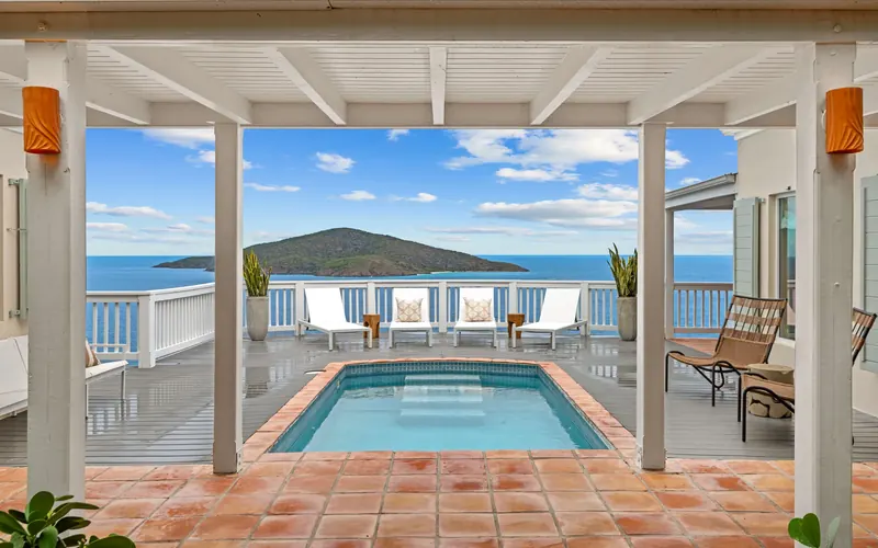 Private pool at Wild Ginger villa framed by the pavilion columns, with the Caribbean and a neighbouring island beyond